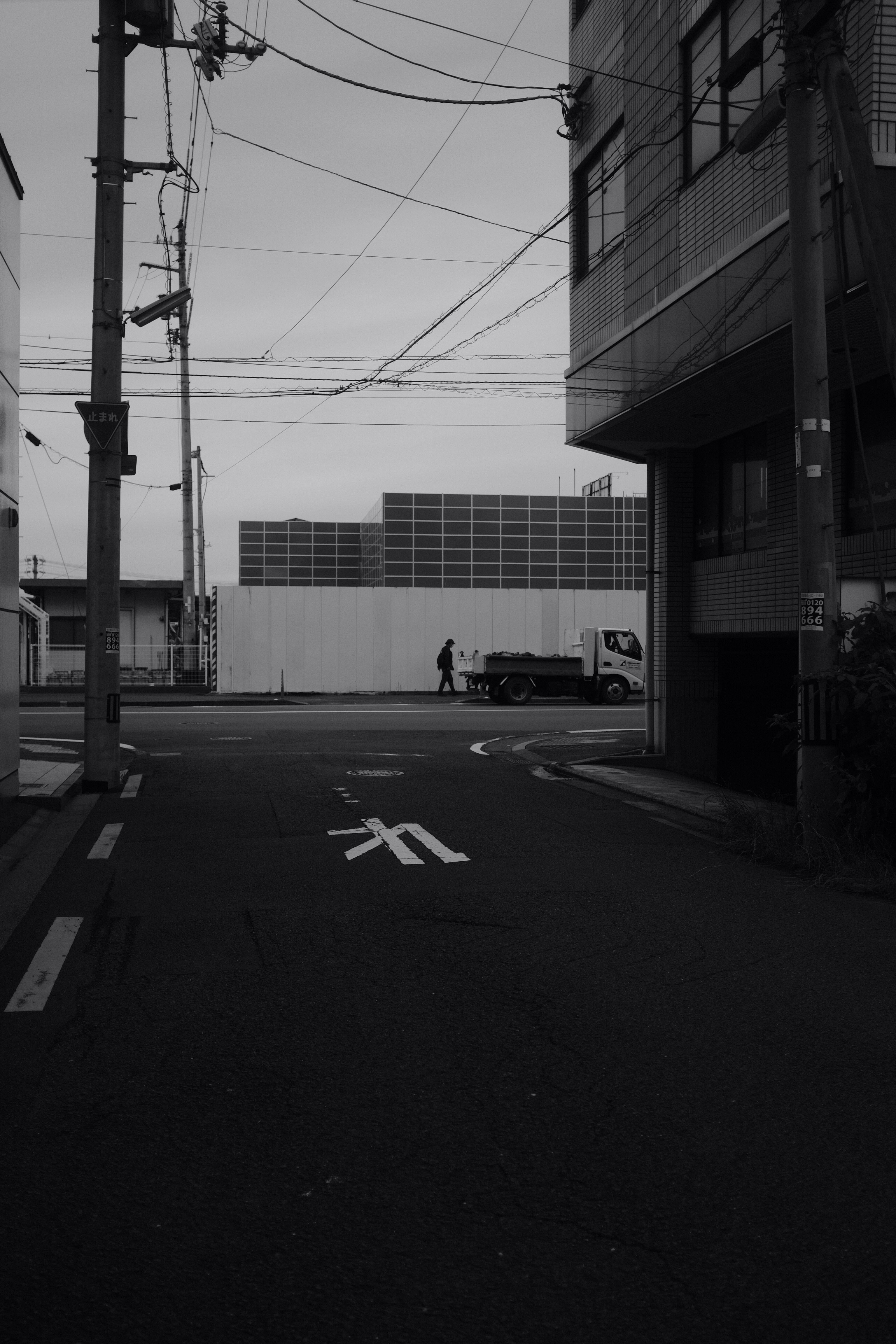 grayscale photo of a road with cars parked on the side